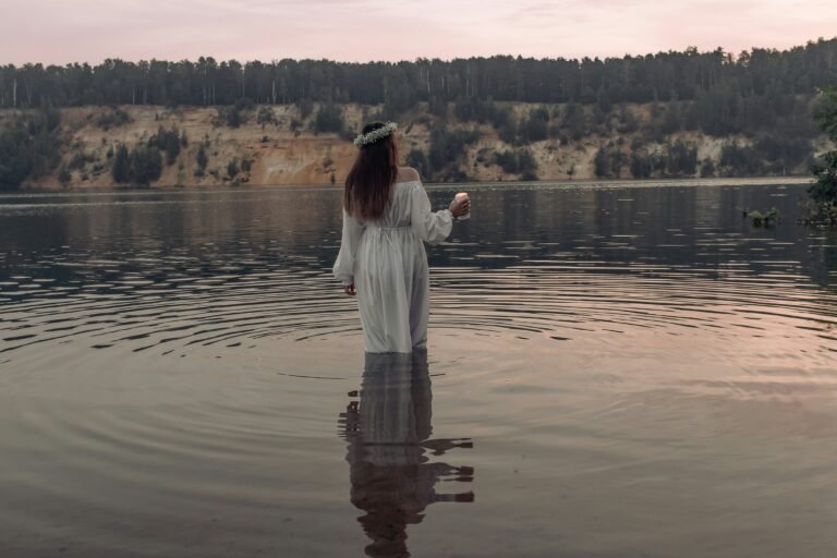 a woman standing in water with a wreath of flowers in her hair